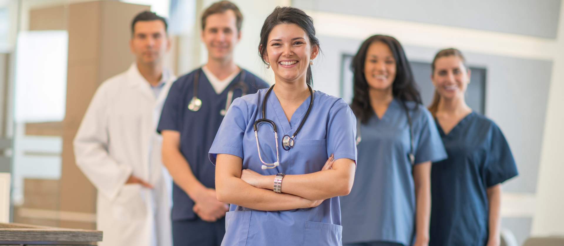 Smiling medical team in blue scrubs standing in a hospital hallway