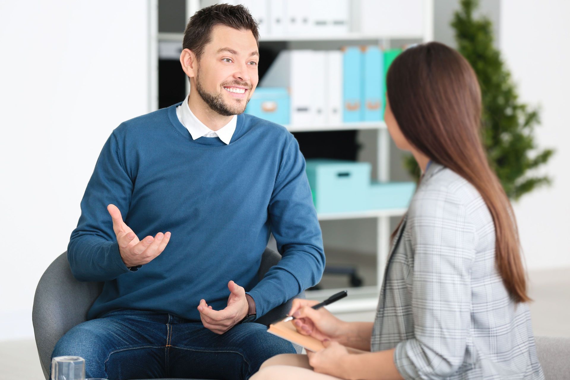Man smiling, gesturing, speaking to person taking notes in a professional office setting. Man smiling, gesturing, speaking to person taking notes in a professional office setting.