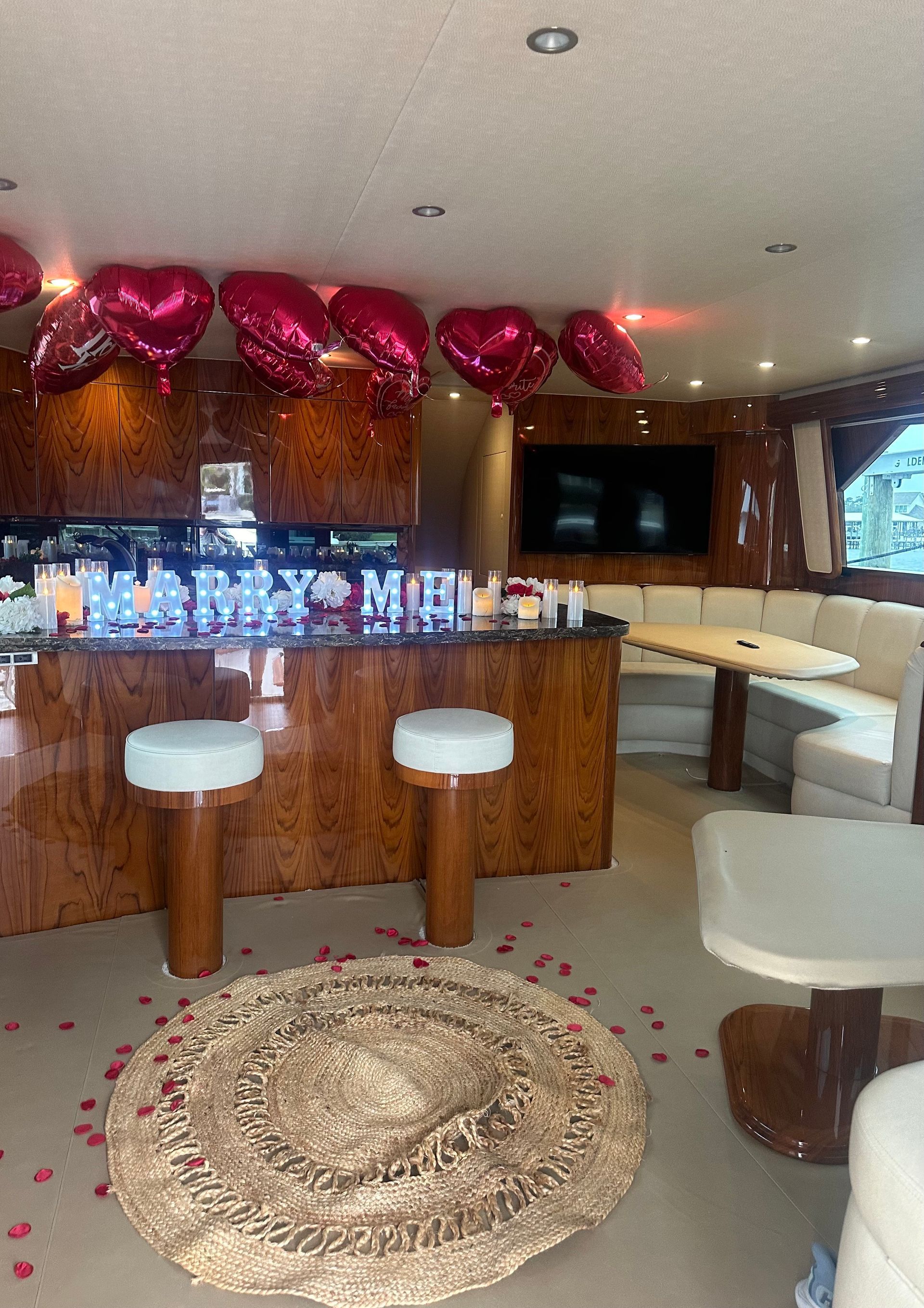Interior of a yacht decorated with heart balloons, bar stools, and a rug.