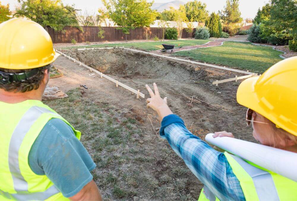 Male and female workers overlooking pool construction site