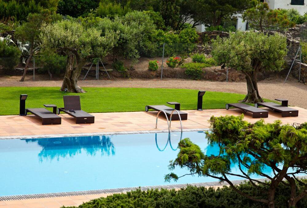 Rectangular pool with trees and beach beds around it