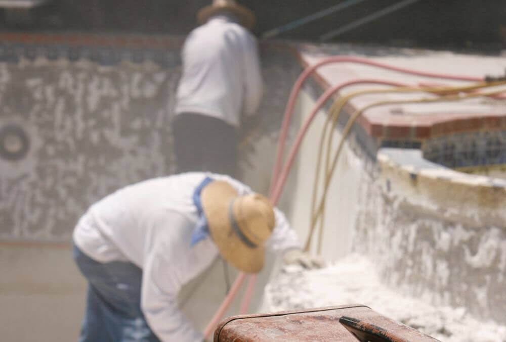 Two workers repairing concrete pool