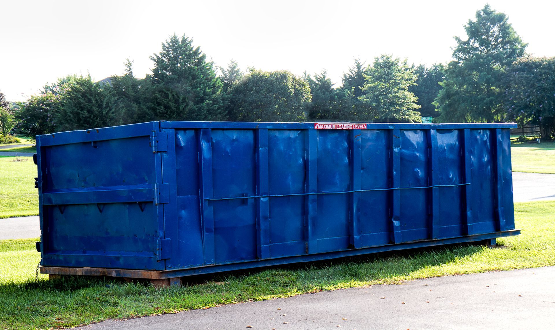 View of a large, blue 20-yard dumpster rental ready to be filled with debris, outdoors.