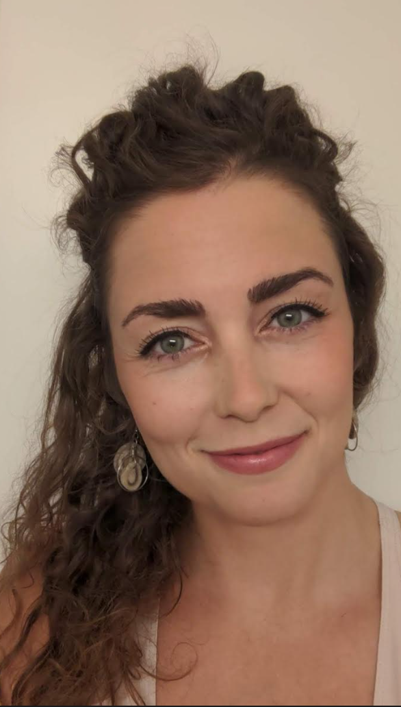 A woman with curly hair is smiling for the camera