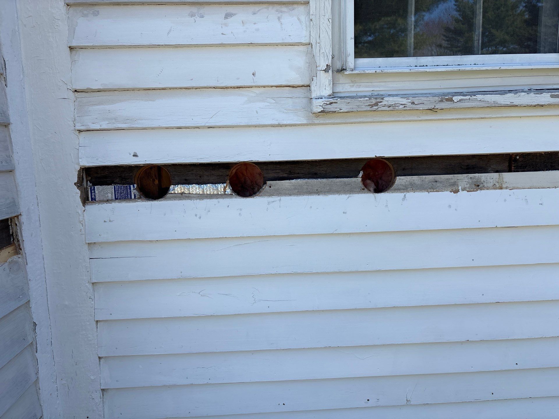 White house siding with a window and a narrow ledge holding three small brown objects