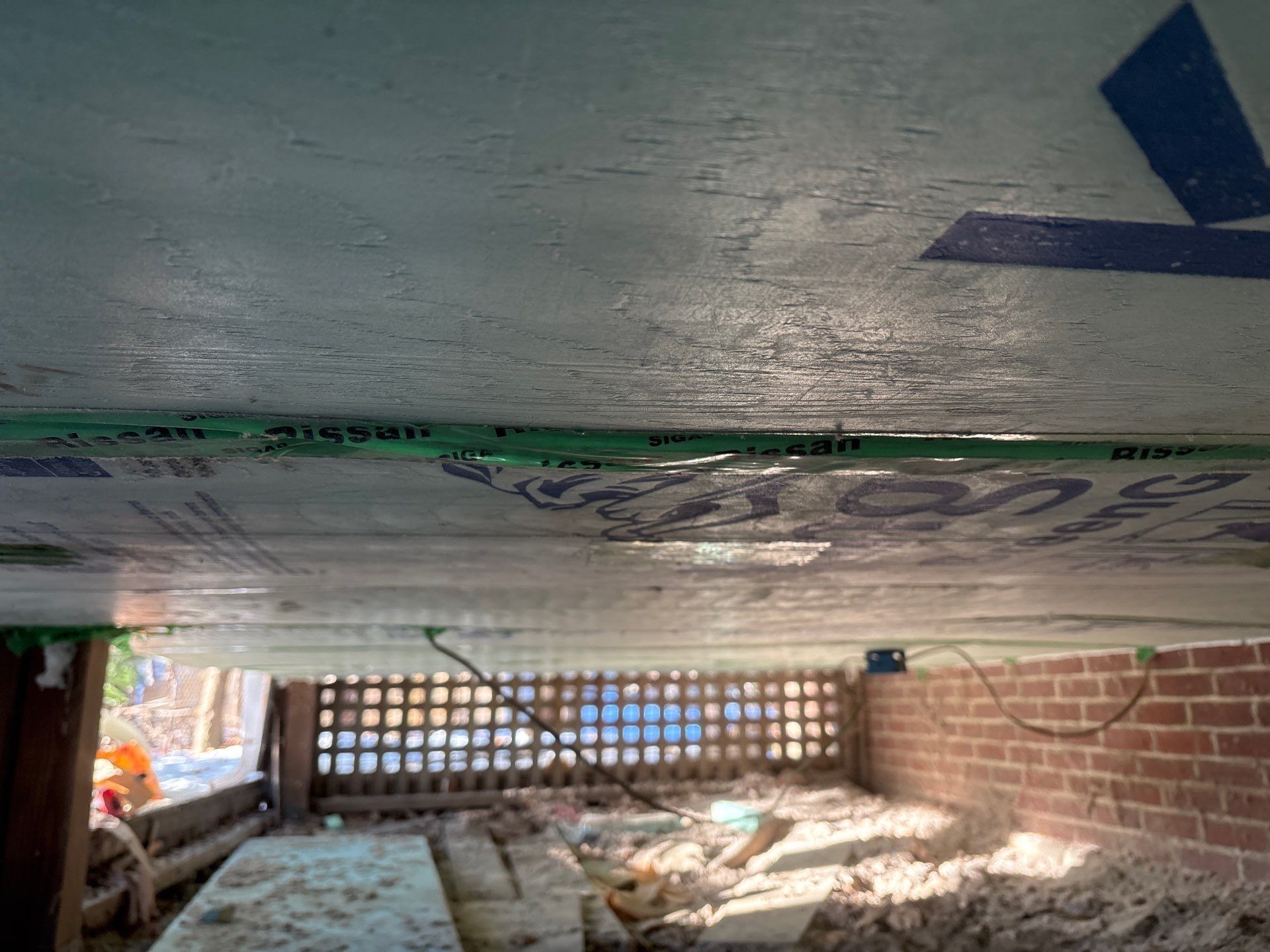 Low-angle view of a brick underpass with a concrete ceiling, debris, and daylight through a block opening
