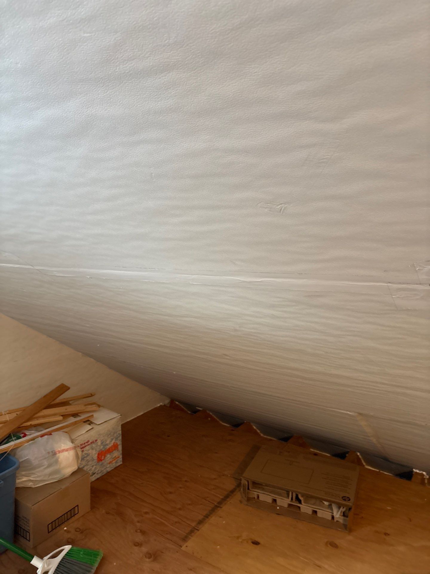 Attic corner with sloped white ceiling and cardboard boxes on a wooden floor
