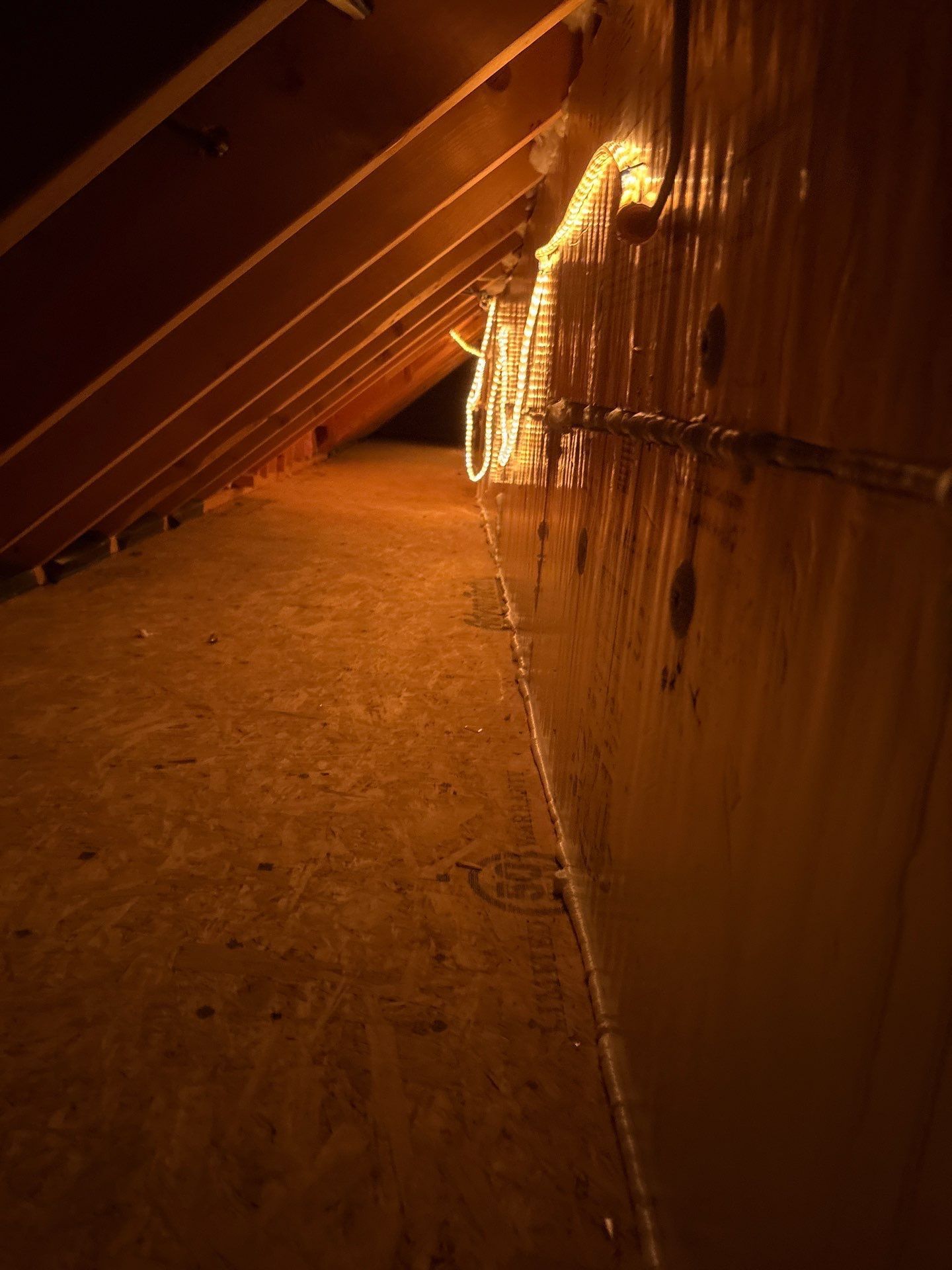 Dim orange-lit corridor with slanted ceiling and textured floor, seen from a low angle