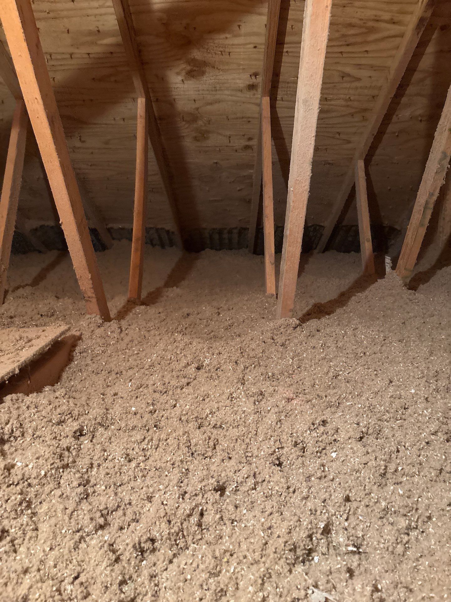 Attic with exposed wooden rafters and a thick layer of blown-in insulation