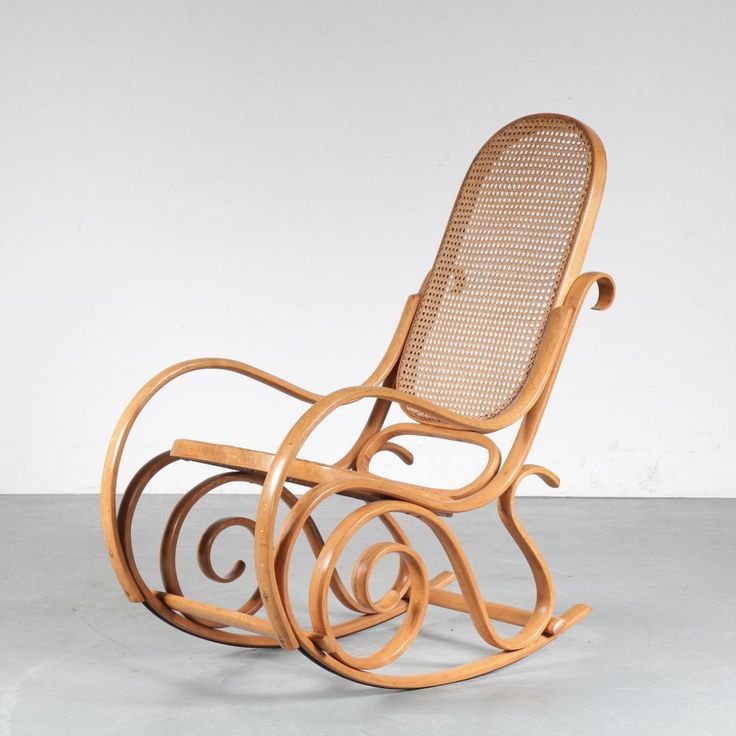 Mecedora de mimbre con estructura de madera curvada y asiento y respaldo de caña tejida, sobre un suelo liso.
