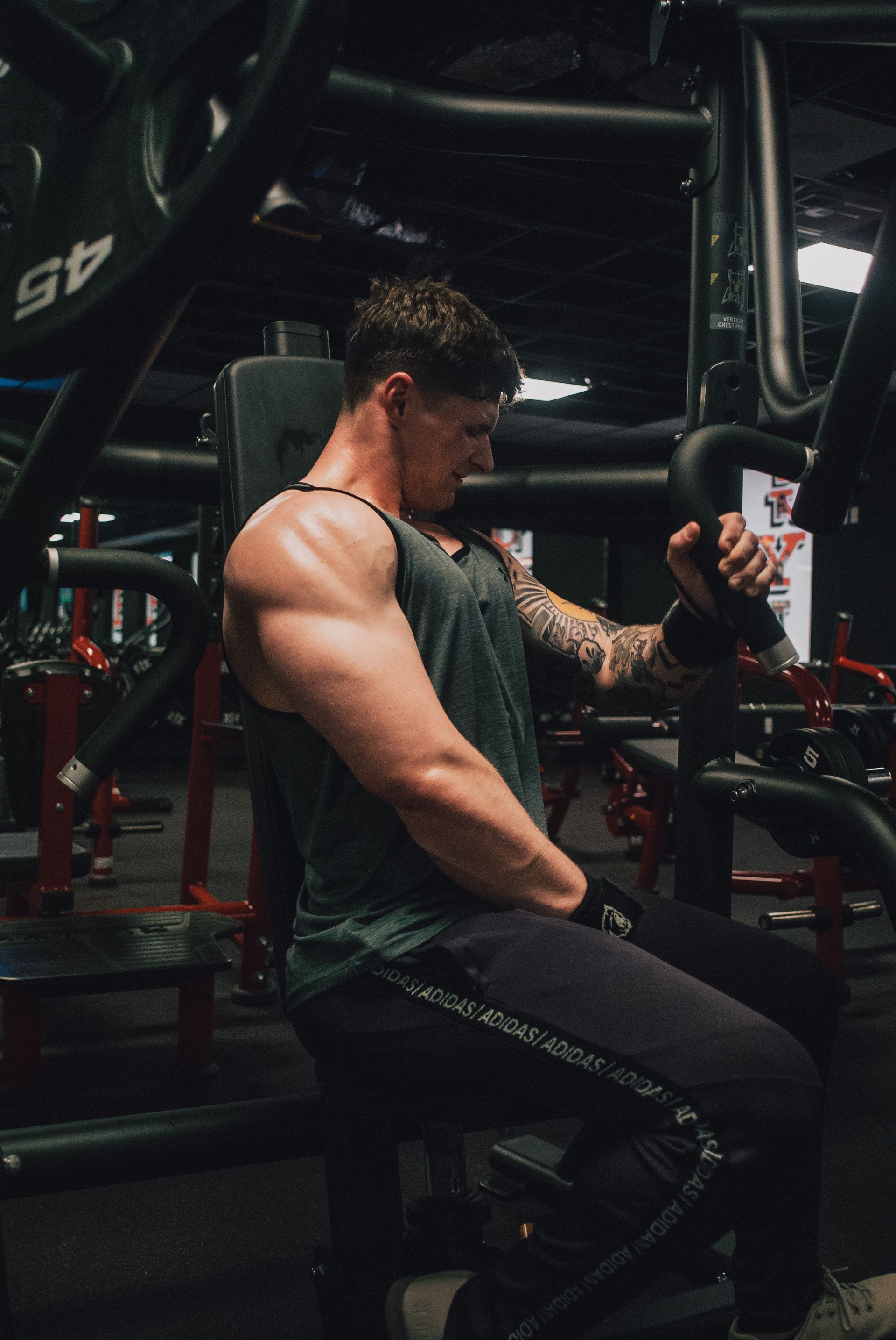 A man is sitting on a machine in a gym.