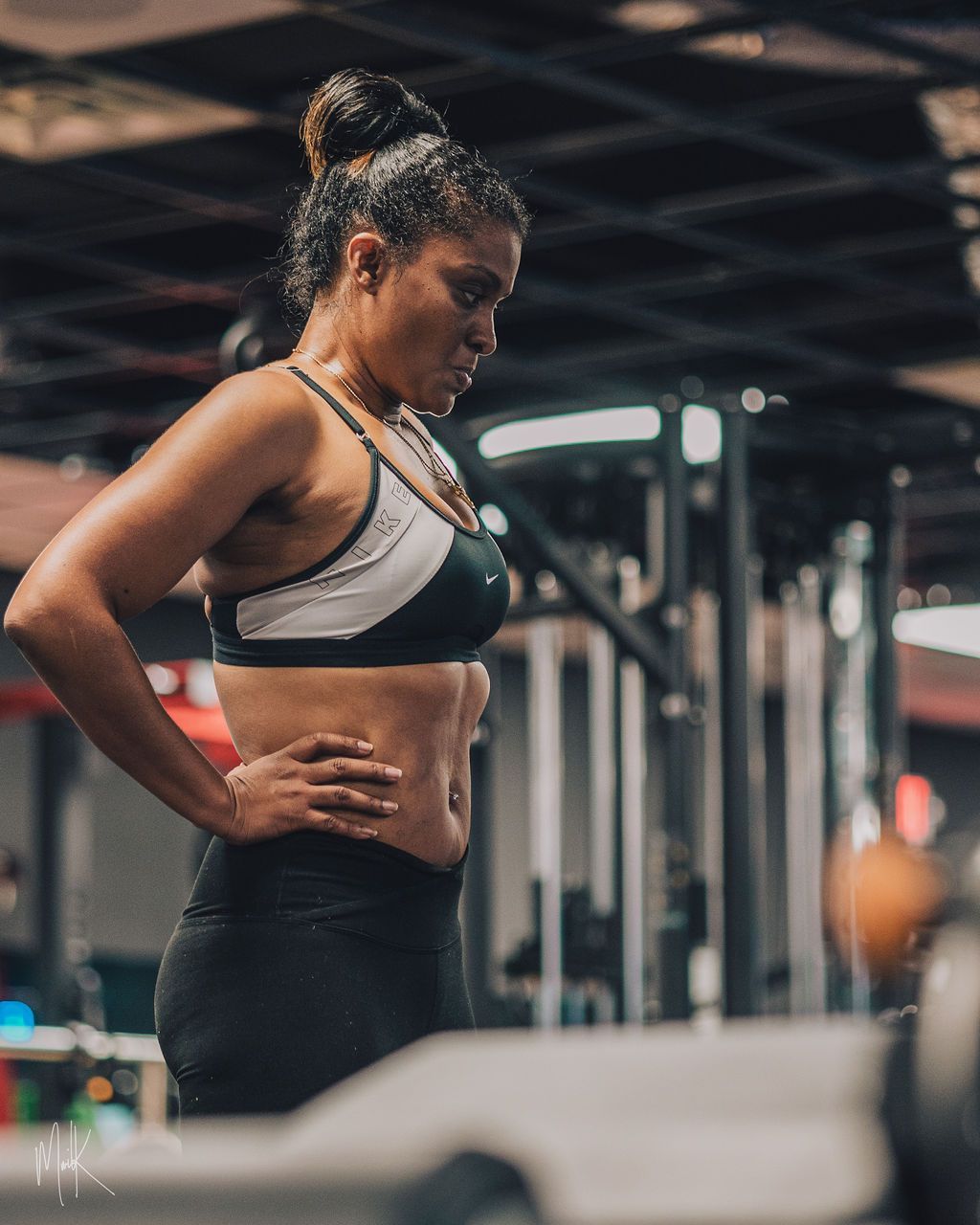 A woman is standing in a gym with her hands on her hips.