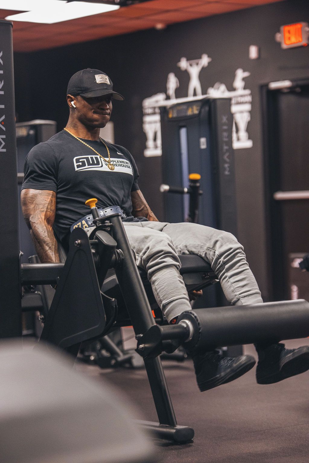 A man is sitting on a leg extension machine in a gym.
