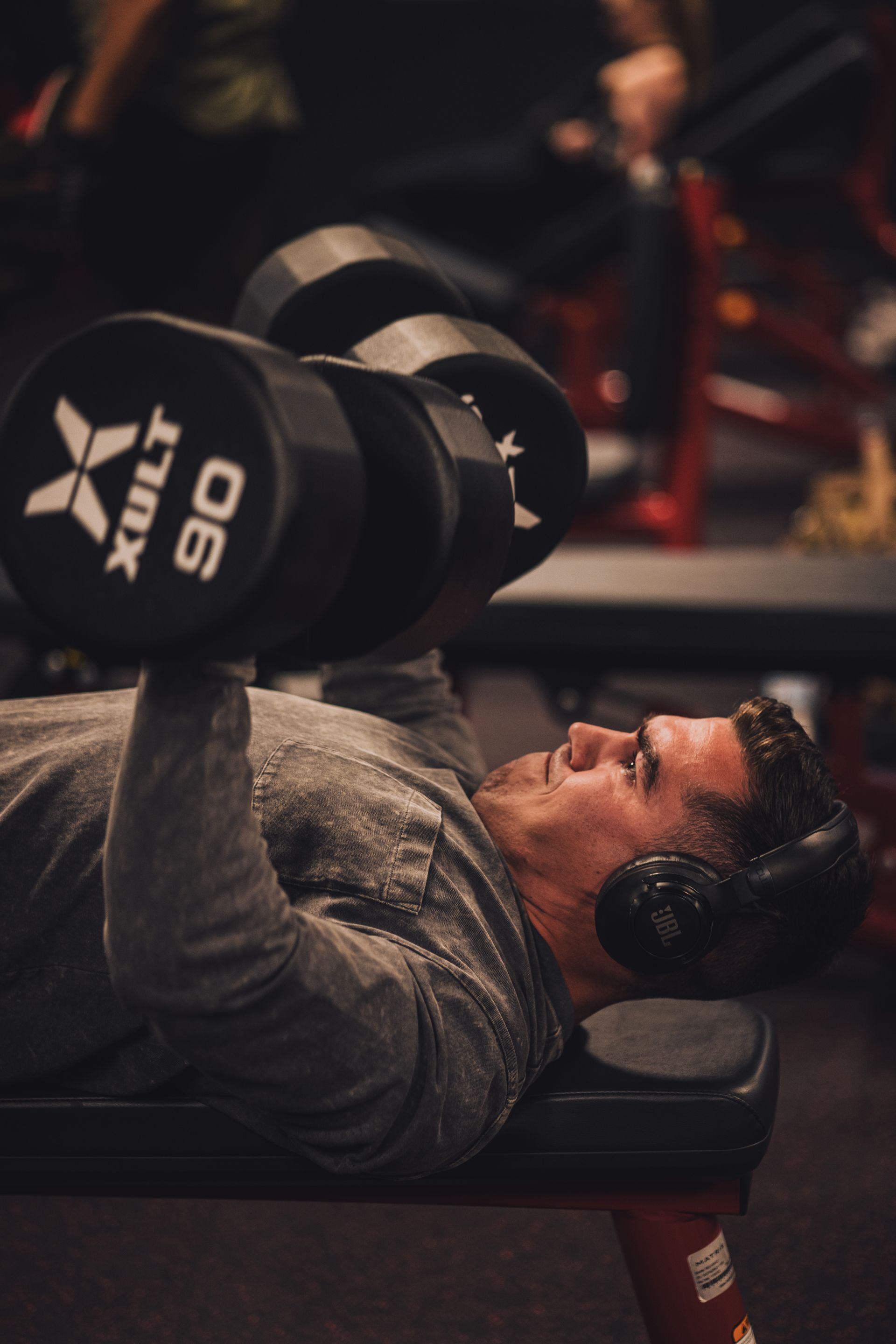 A man is laying on a bench lifting a dumbbell.