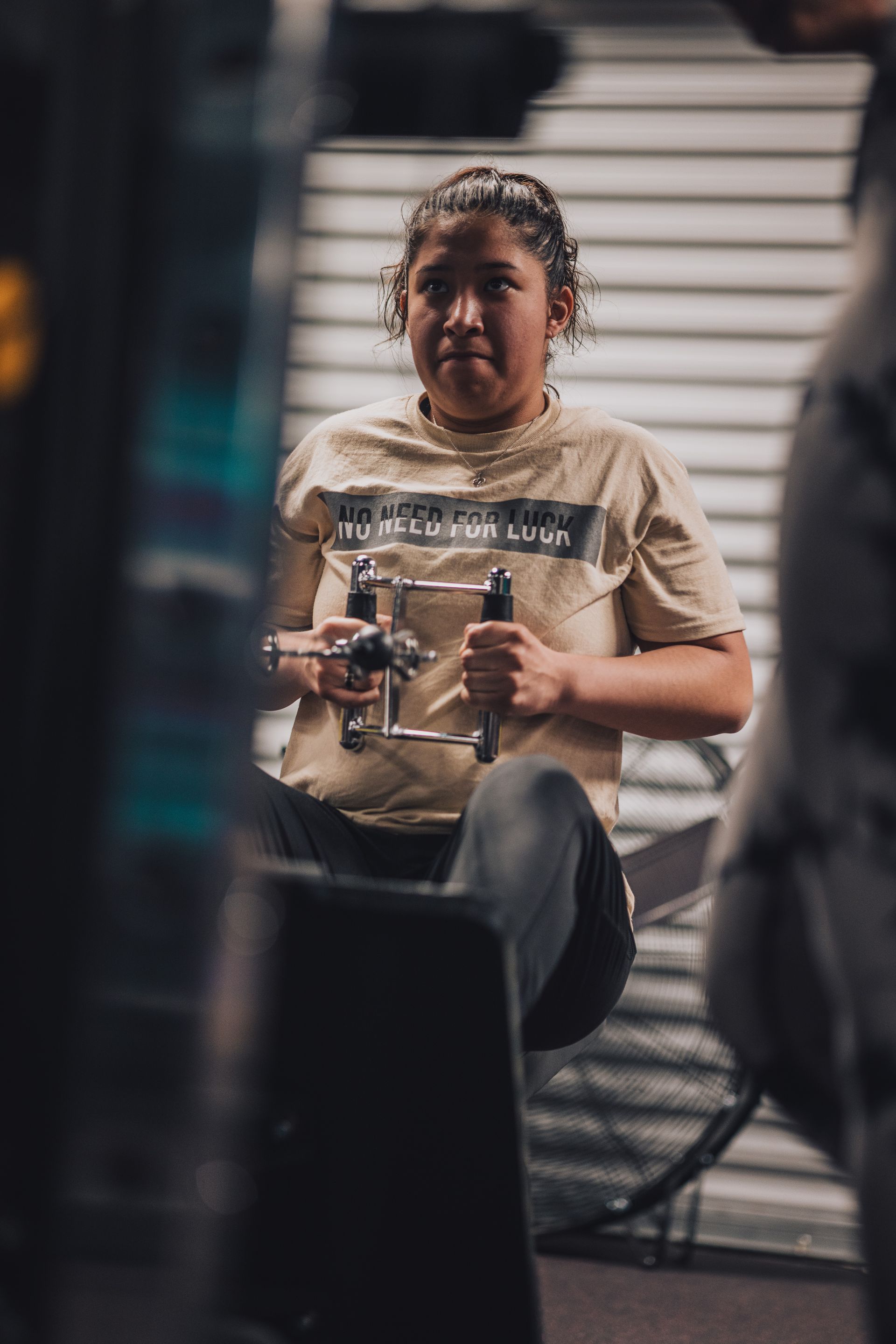 A woman is sitting on a machine in a gym.