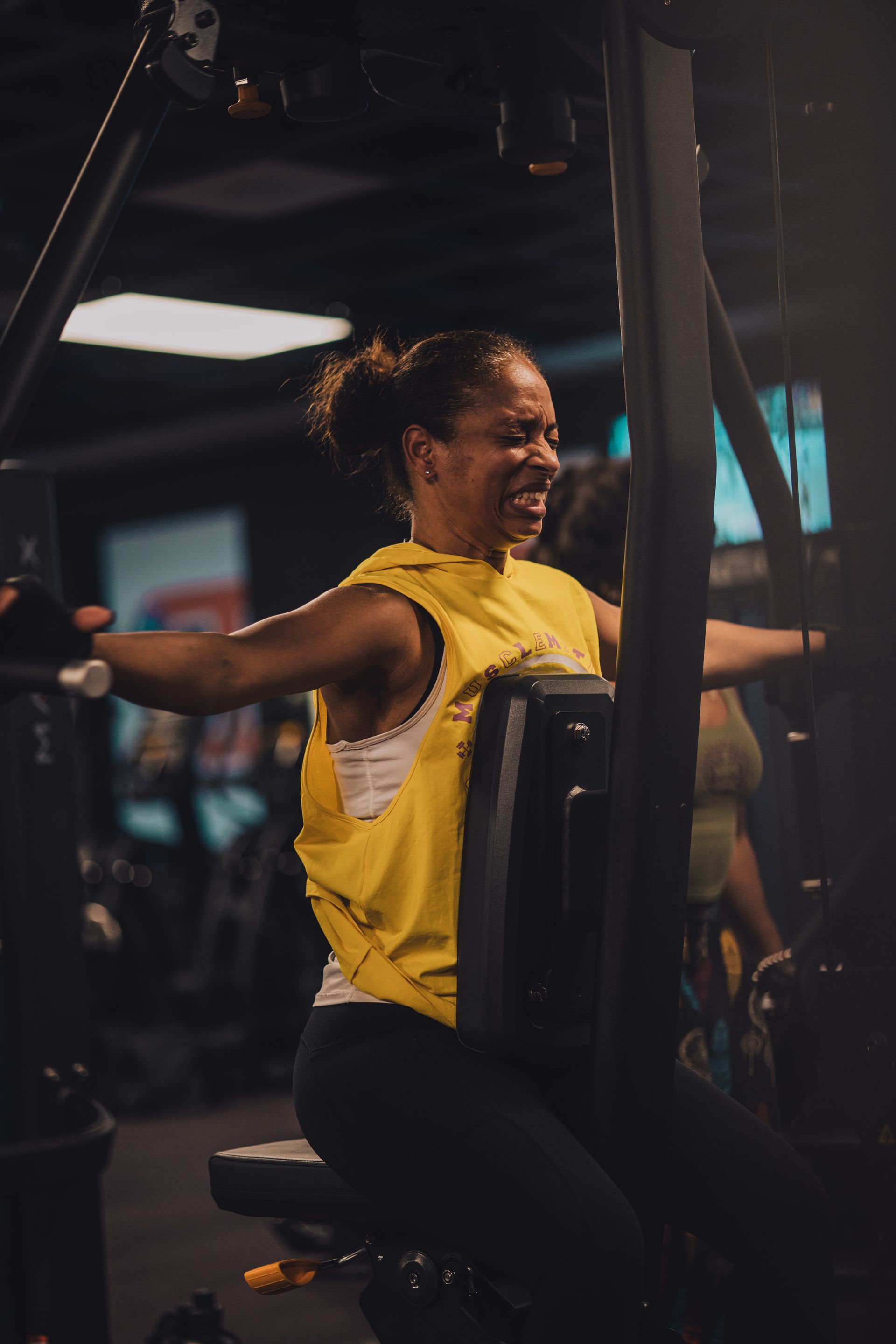 A woman is sitting on a machine in a gym.