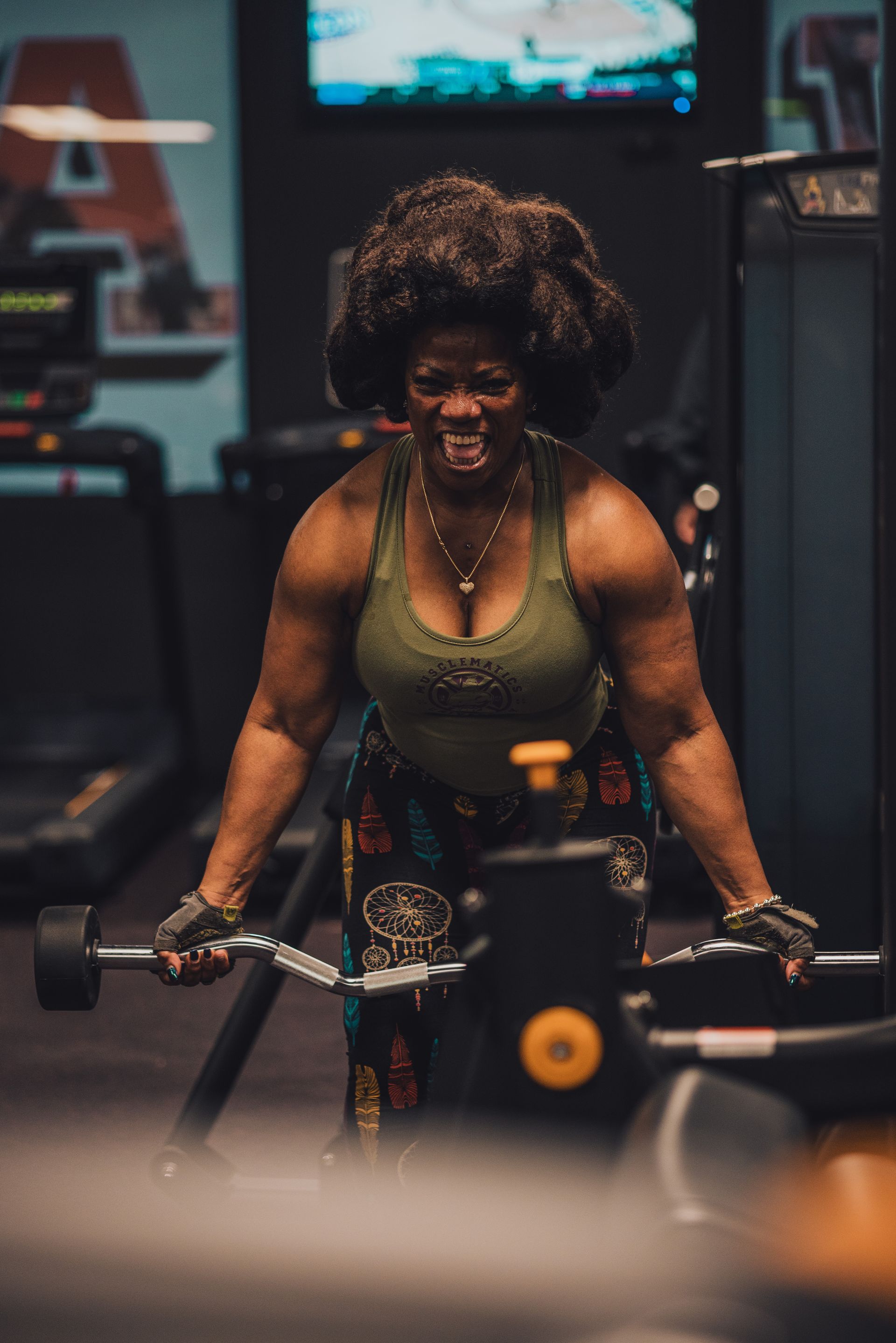 A woman is lifting a barbell in a gym.
