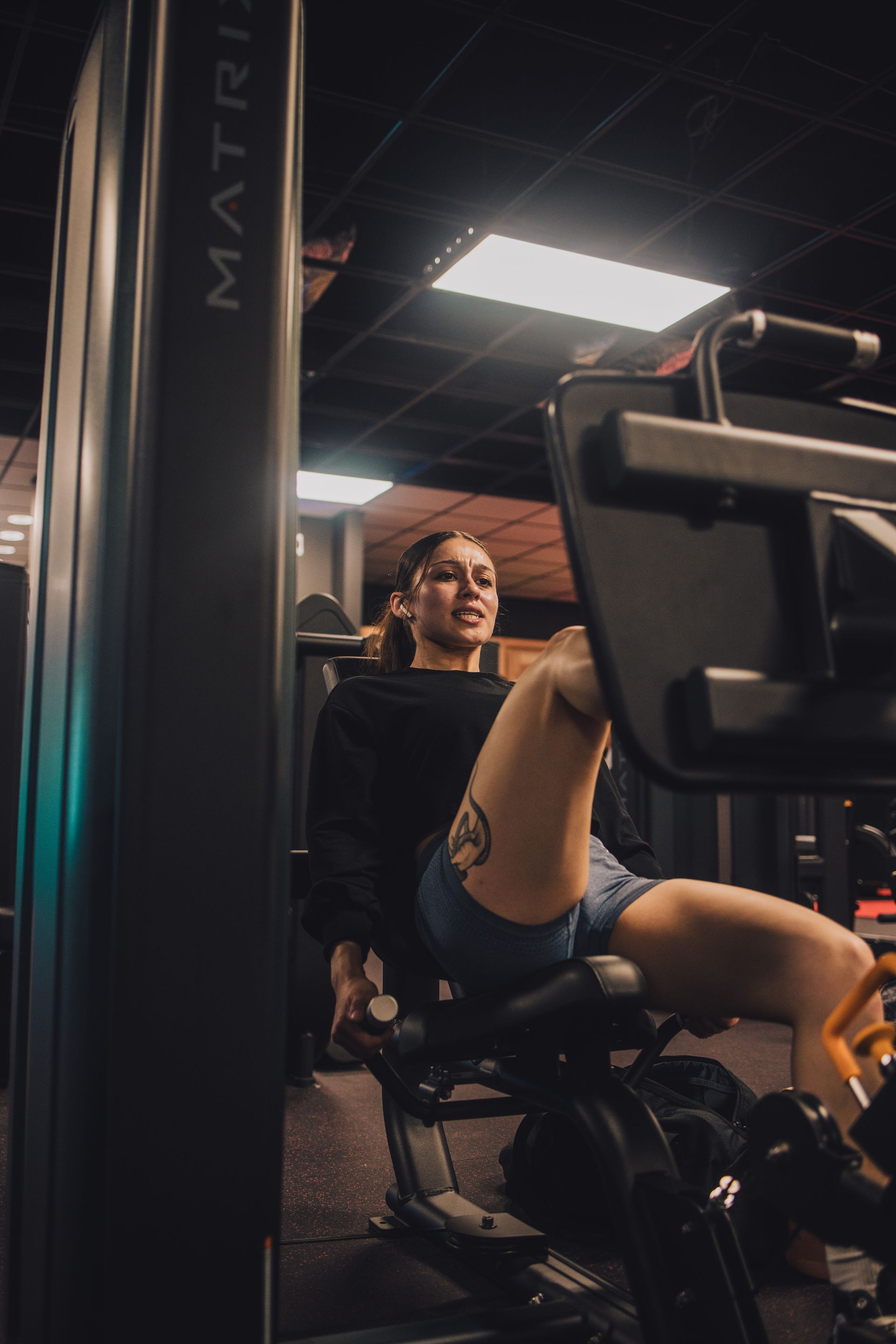 A woman is sitting on a machine in a gym.