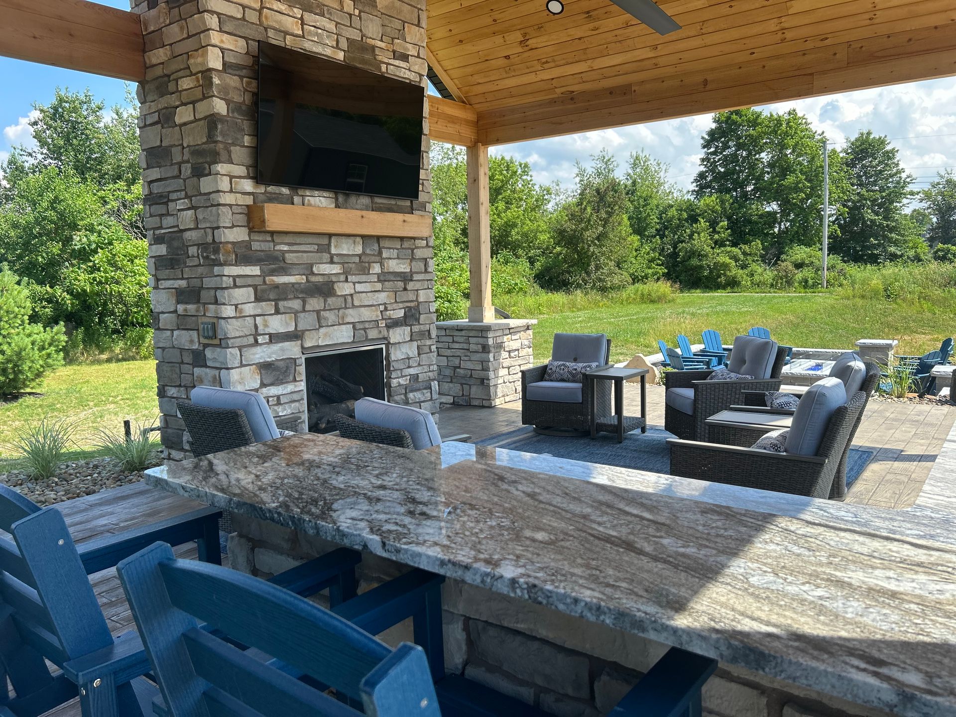 Outdoor patio with stone fireplace, bar seating, and lounge area.