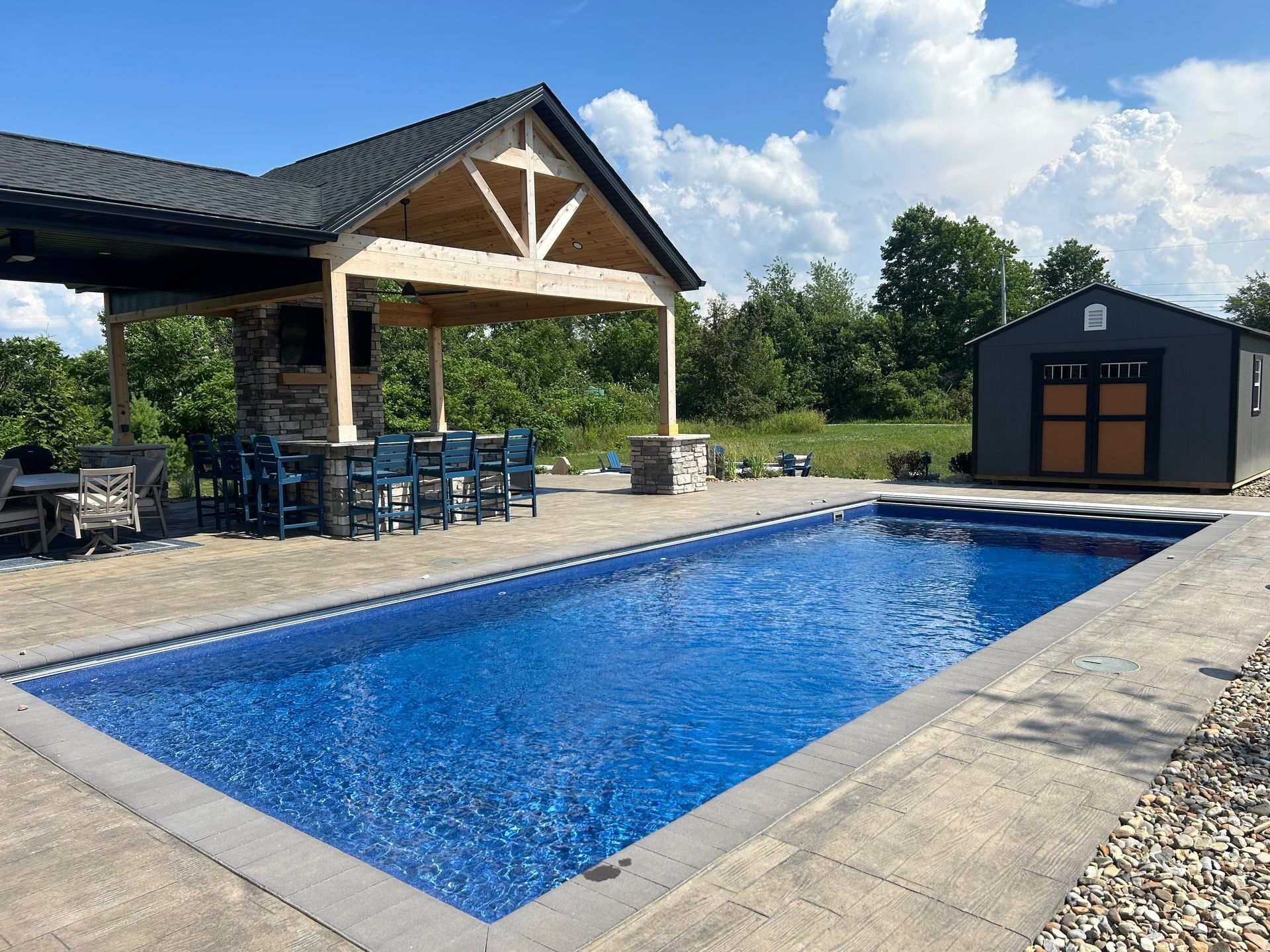 Rectangular pool with bar and shed on sunny day.