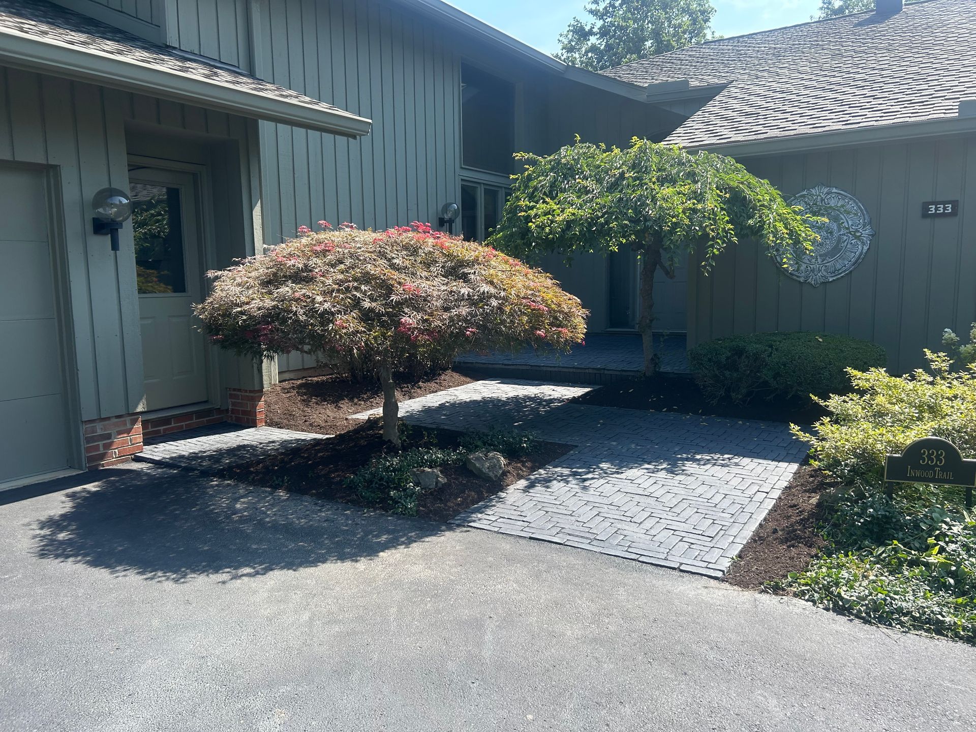 House entrance with Japanese maple tree, paved walkway, and landscaping.