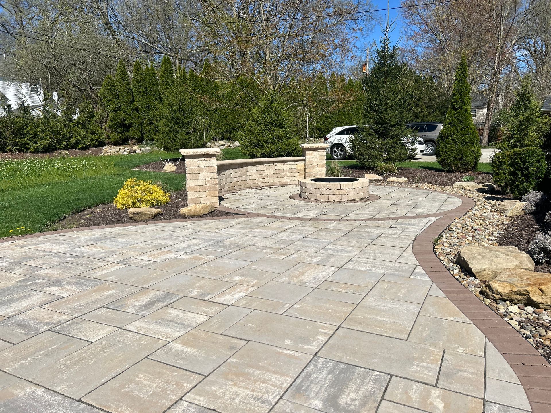 Stone patio with fire pit, seating wall, and landscaping.