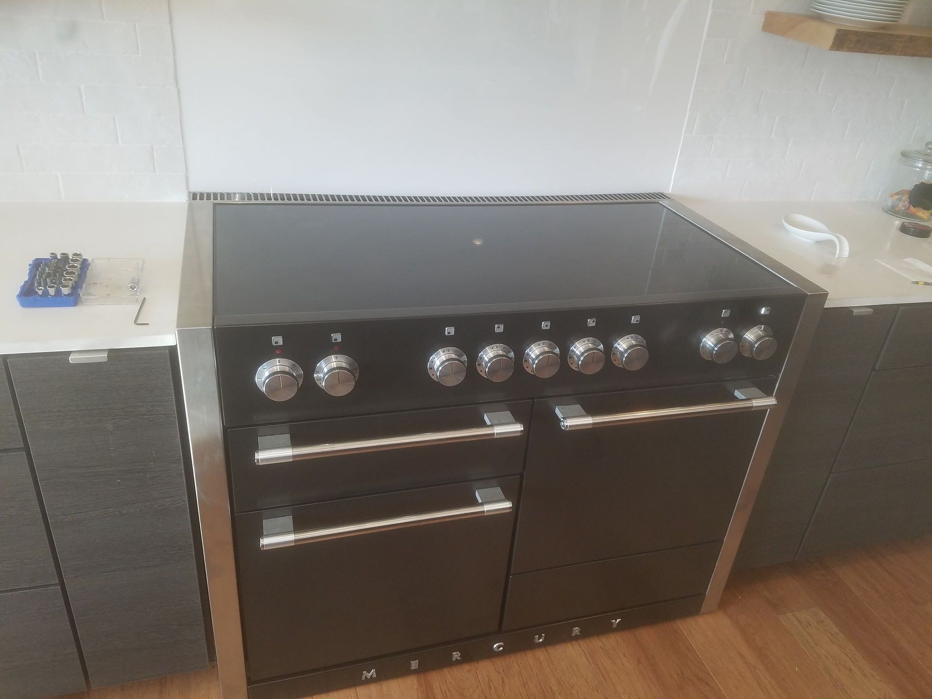 Black freestanding range cooker with oven doors in a kitchen, against a white wall and wood floor