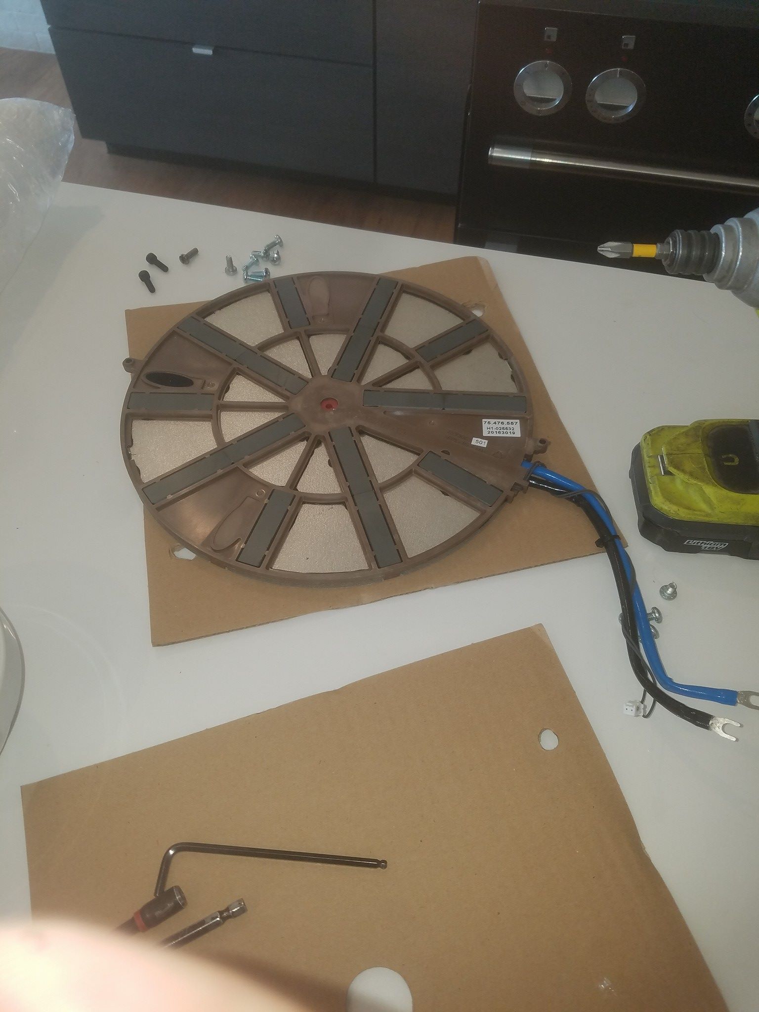 Workbench with a circular segmented device, blue cable, and tools on cardboard panels