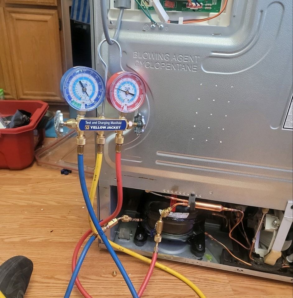 Blue and red HVAC gauges with hoses attached to a unit in a wooden-floored room