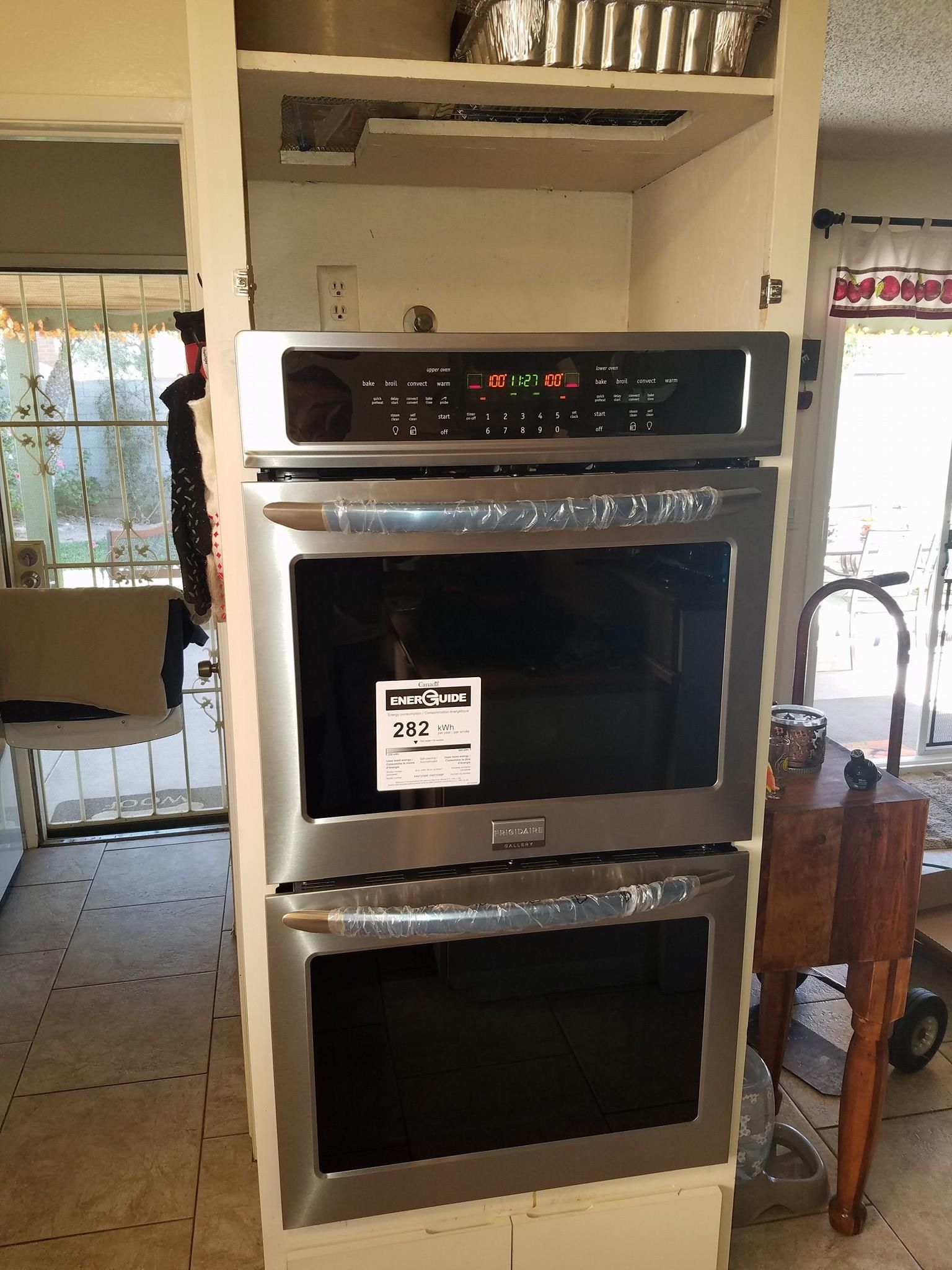 Built-in double oven with stainless steel trim in a kitchen alcove, front view