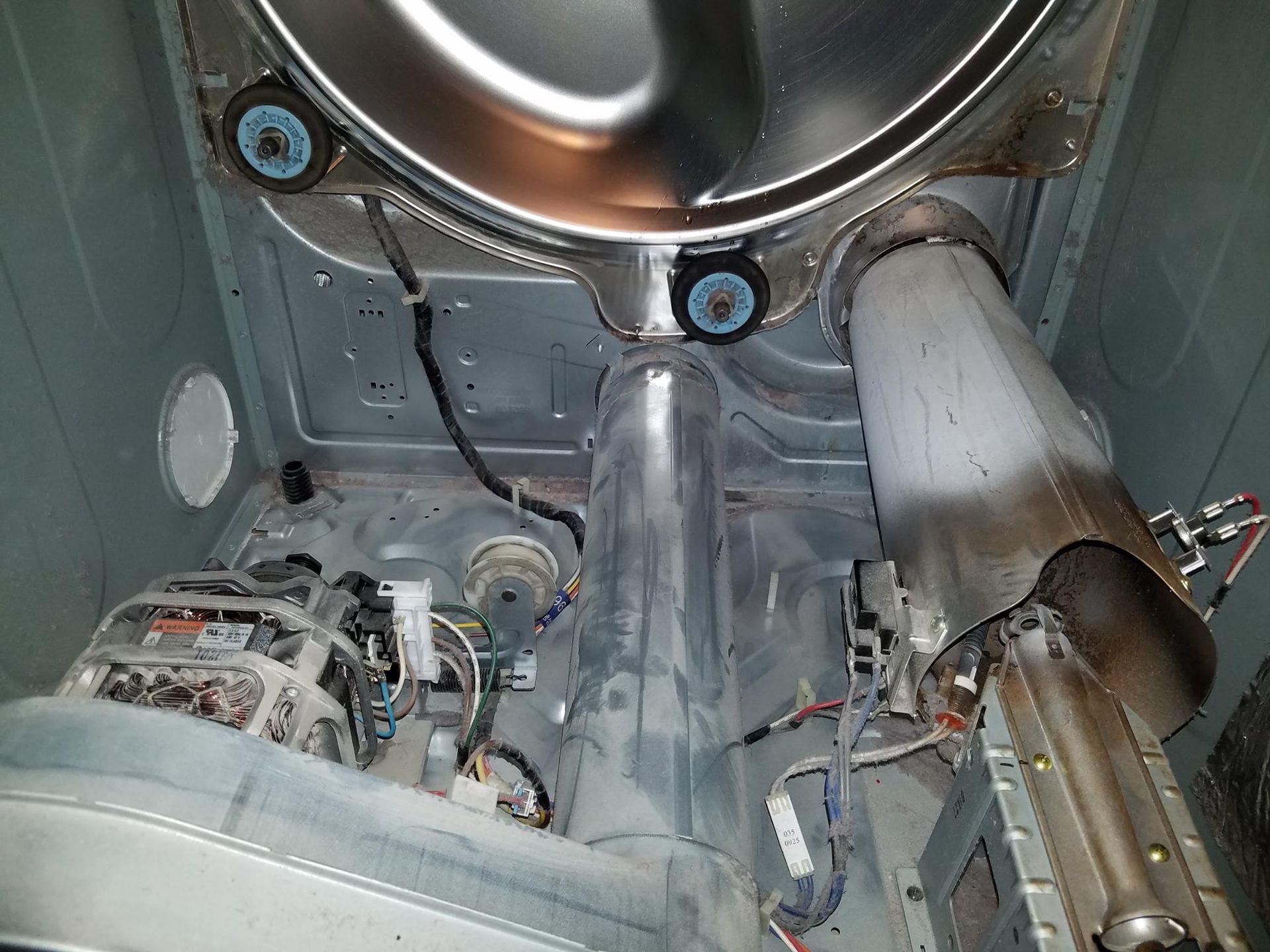 Inside a metallic machine chamber with pipes, cables, and a round hatch overhead