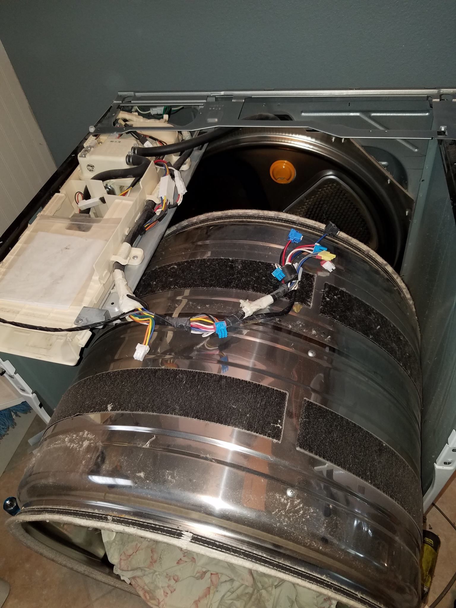 Industrial machinery with large shiny cylindrical drum and exposed mechanical components inside a metal housing