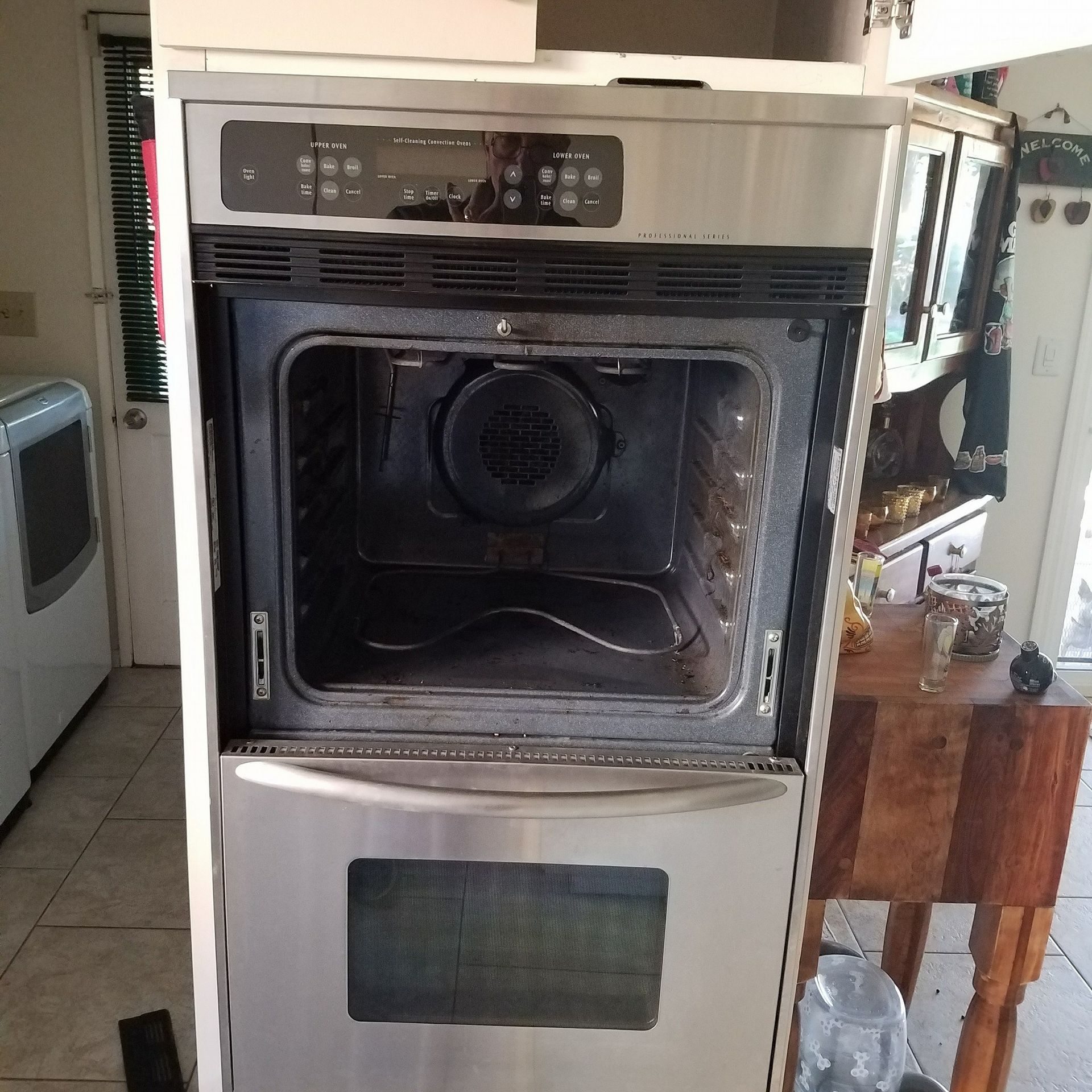 Stainless steel wall oven with open door, showing a dark interior in a kitchen.