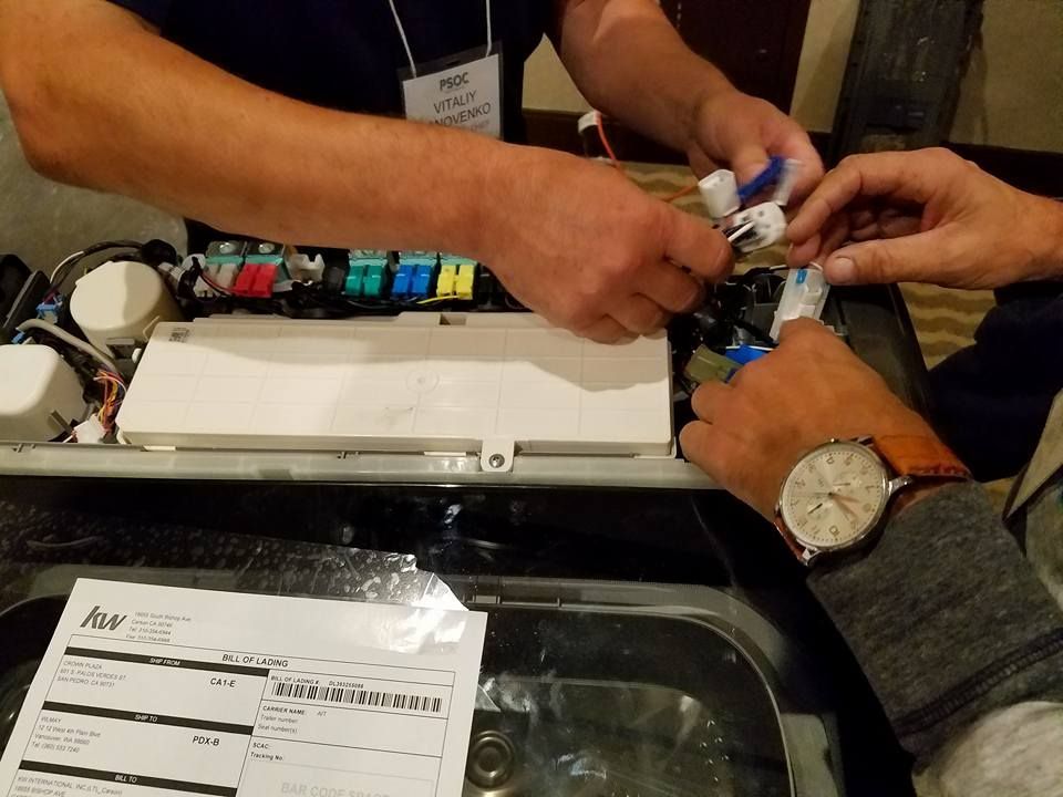 Hands working on electronic components inside an open device on a table