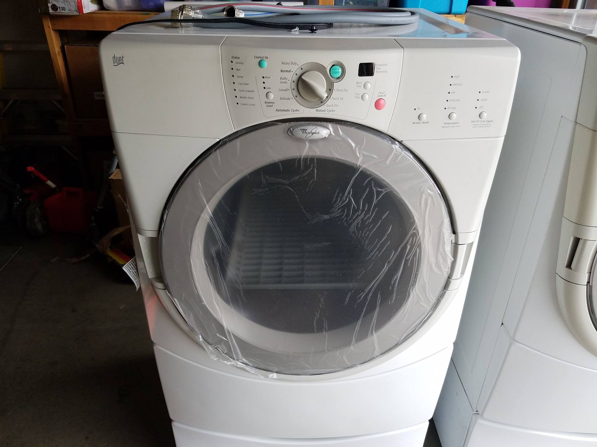 White front-load washing machine with a round glass door and control panel in a laundry area
