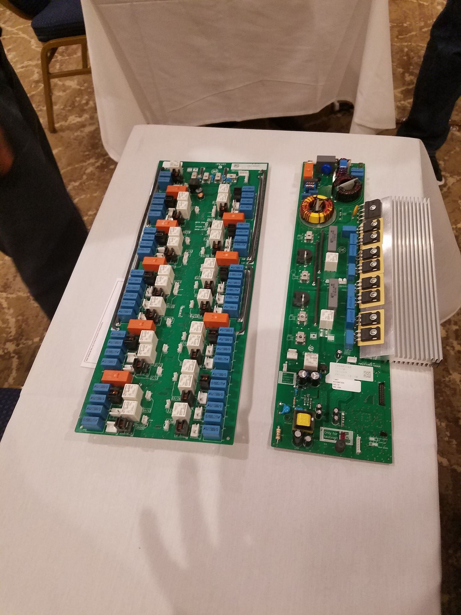 Two green circuit boards with electronic components laid on a white cloth-covered table