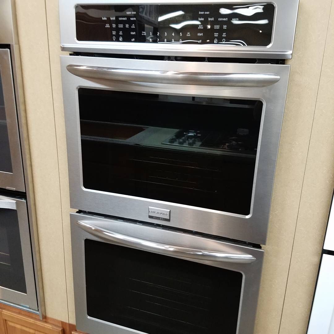 Stacked stainless steel wall ovens in a kitchen display wall.