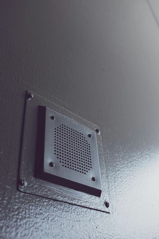 Hands using an adjustable wrench to tighten a valve on a white radiator.
