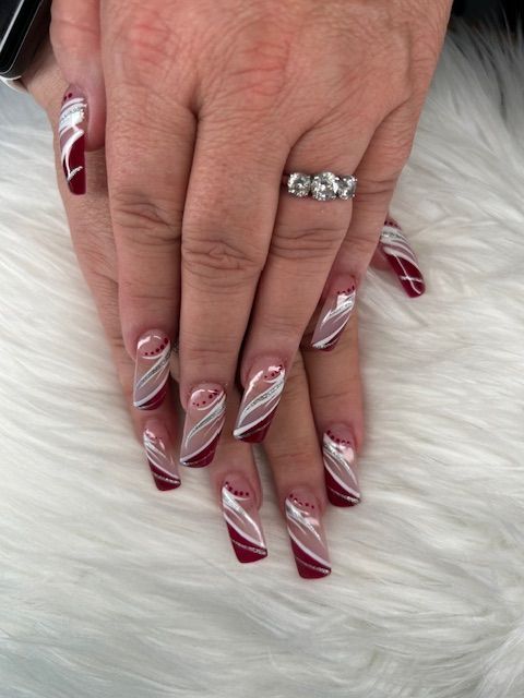 A woman 's hand with long red and white nails and a ring on her finger.