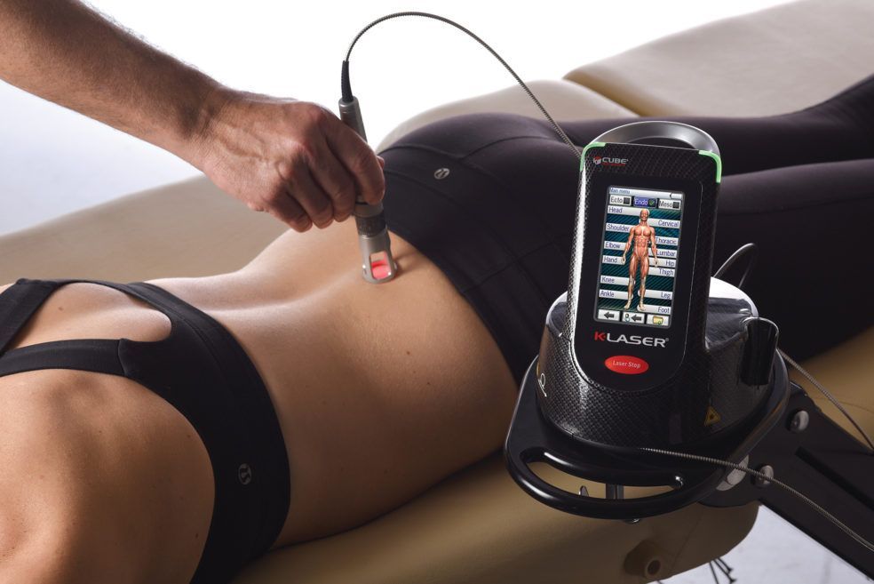 Hand applying a probe to lower back while a monitor displays ultrasound scan results