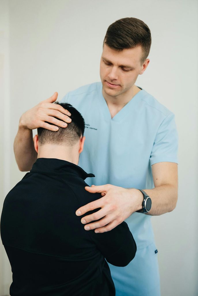 Medical professional examining a patient’s neck and head in a clinic
