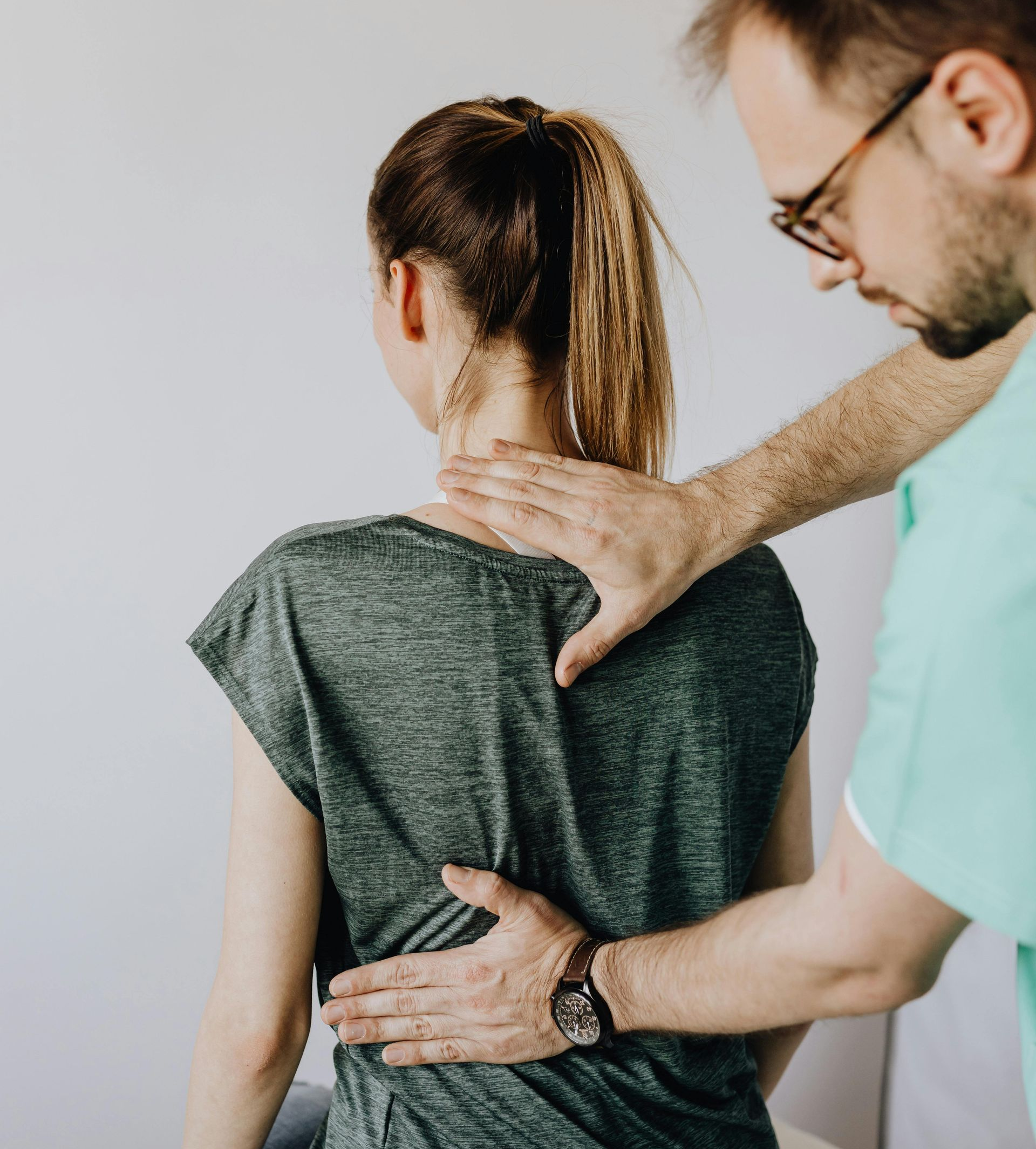 Physical therapist examining a patient’s back and shoulder in a clinic
