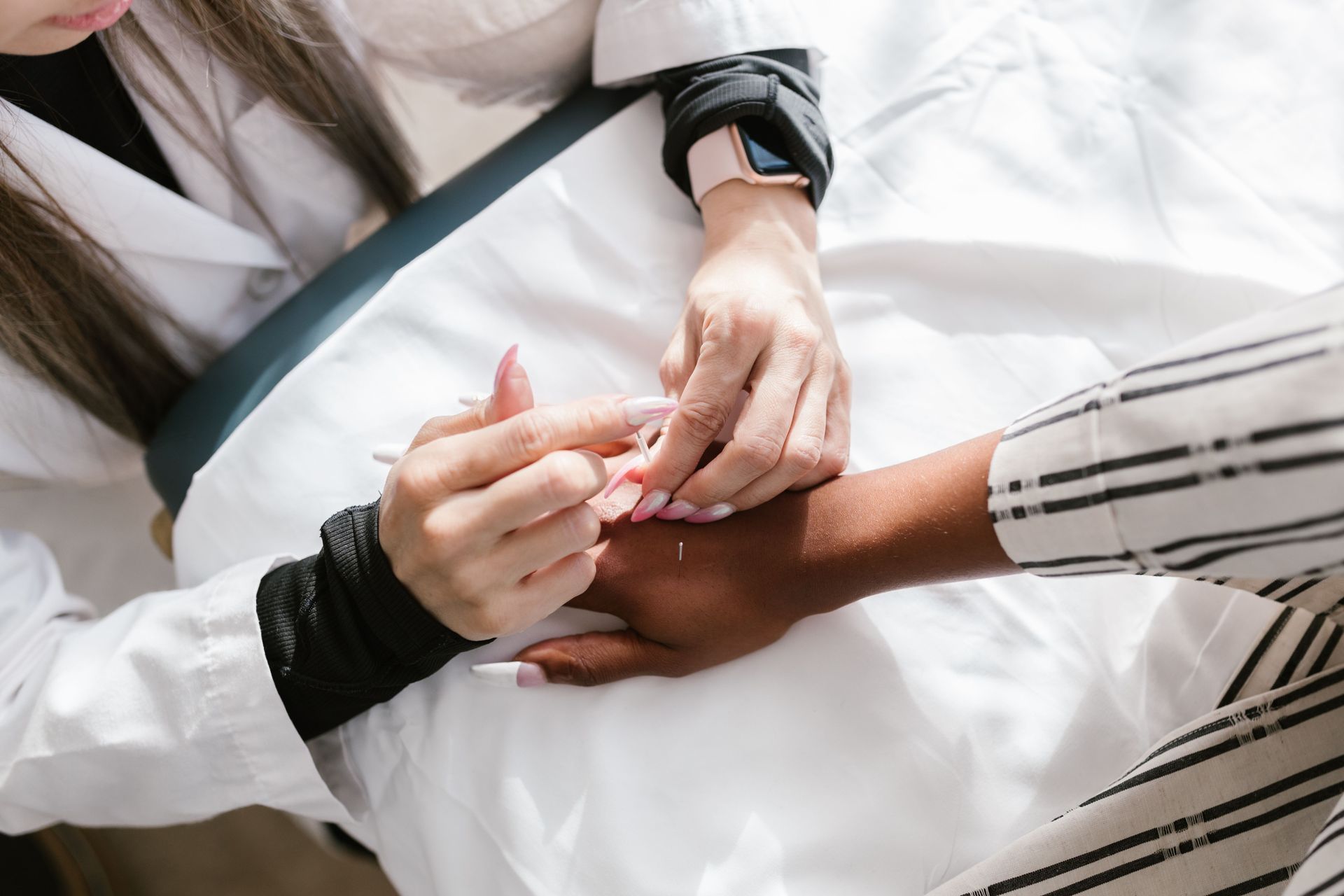 Hands stacked together in a supportive group gesture over white clothing