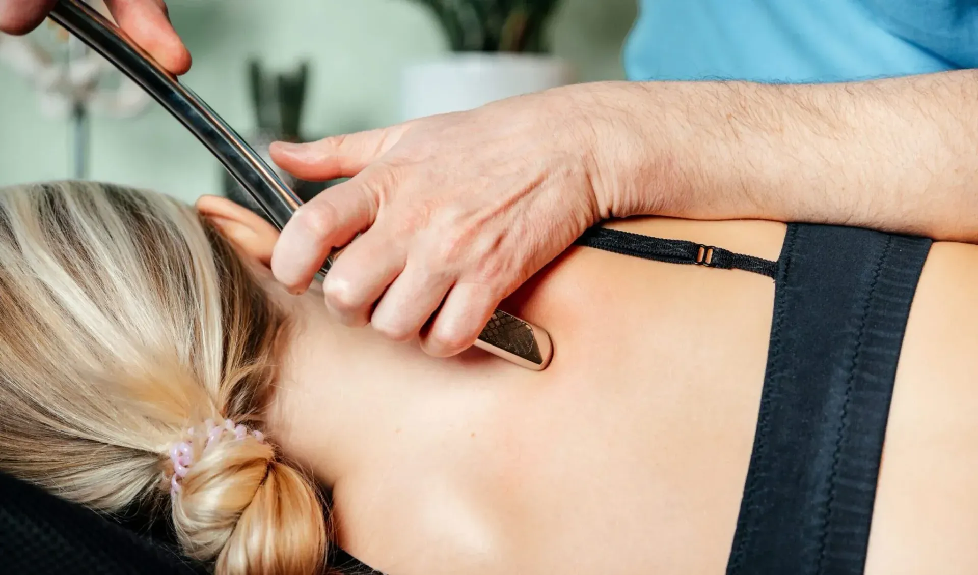 Two massage therapists working on a client lying face down on a treatment table