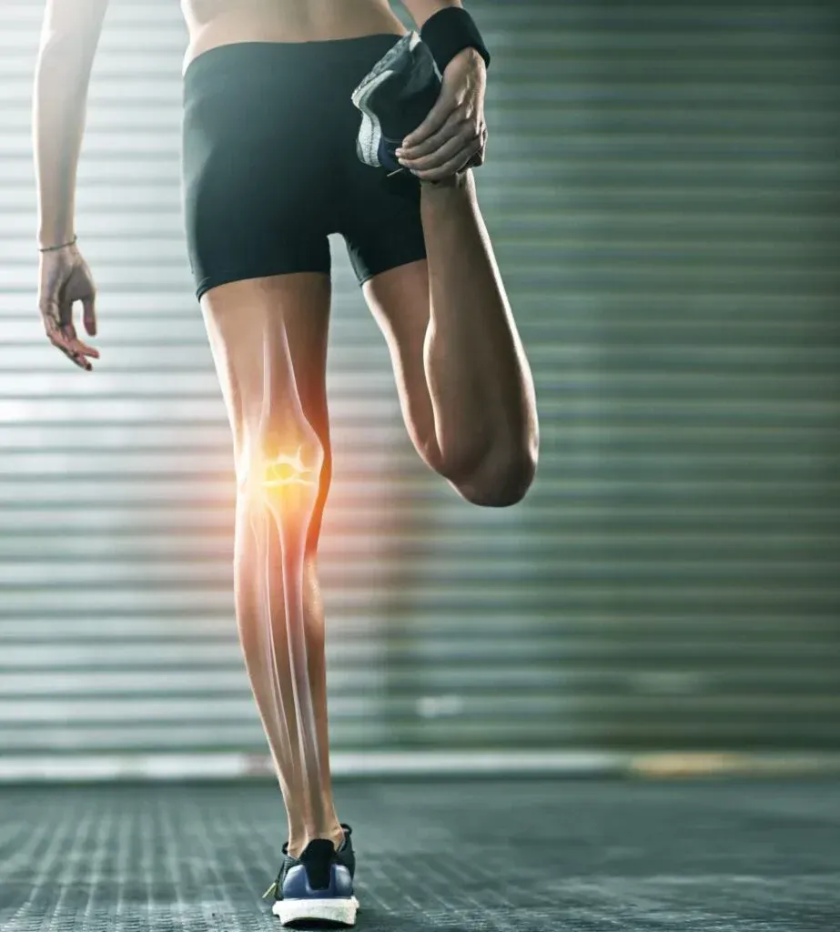 Runner holding a knee with glowing pain highlight, standing on a gym floor