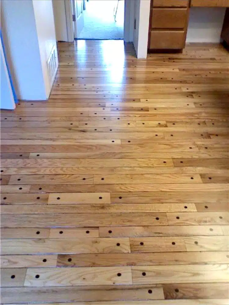 A wooden floor with holes in it in a room.