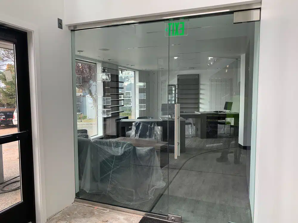 A room with a glass door and a green exit sign.