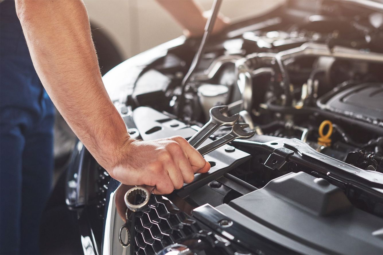 Mechanic tightening a bolt in an open car engine bay