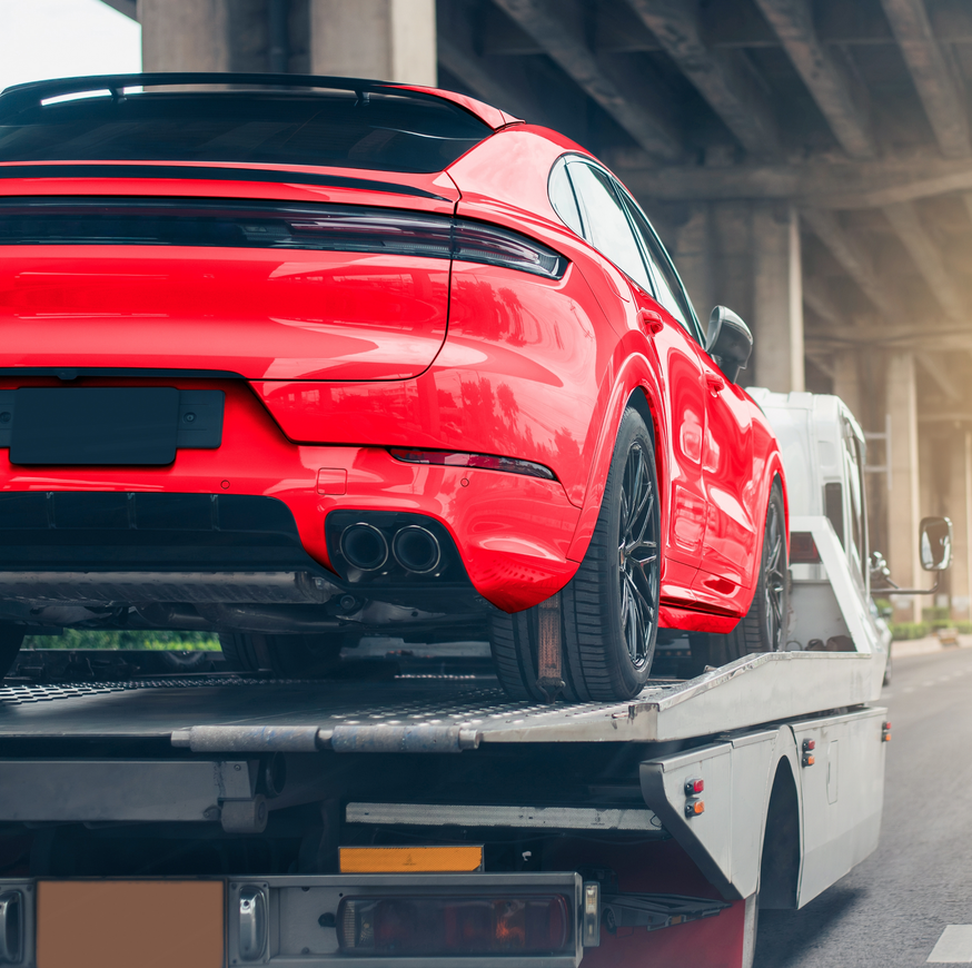 Red sports car on a tow truck inside a garage