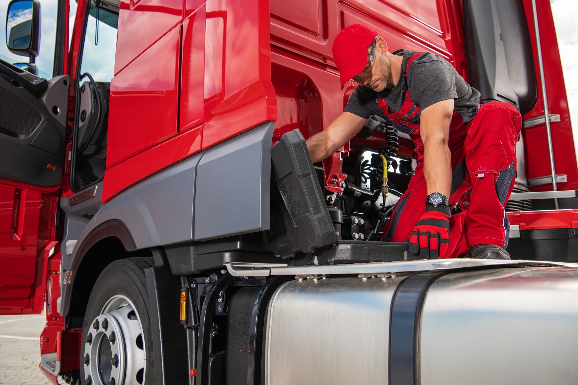 Mechanic working under the hood of a red truck in a garage